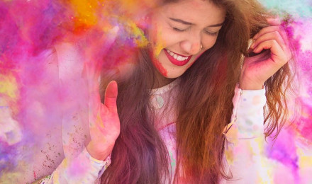 Woman in white long sleeve shirt with purple yellow and blue powder on her face photo