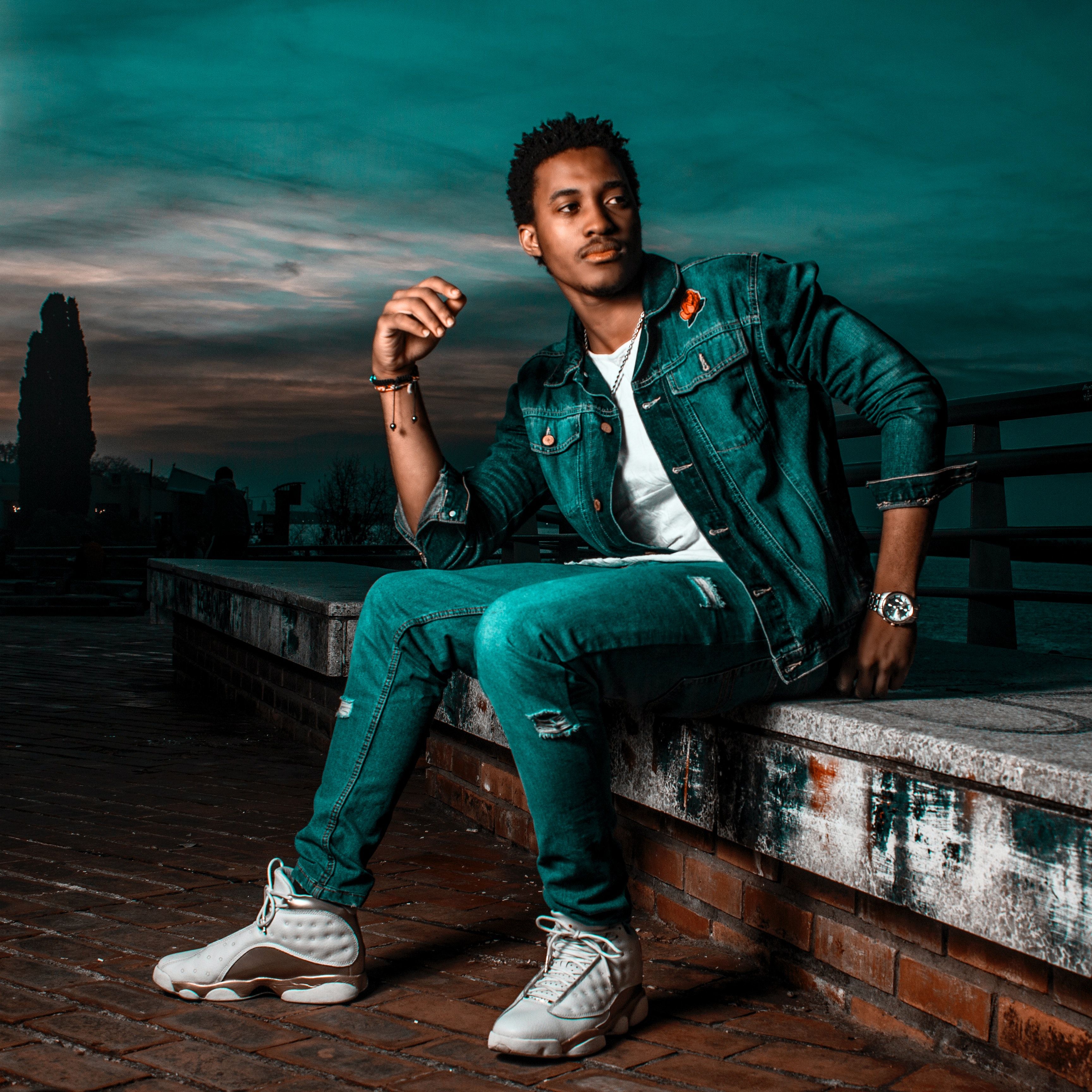 Man in Blue Denim Jacket and Jeans Sitting on Concrete Slab · Free