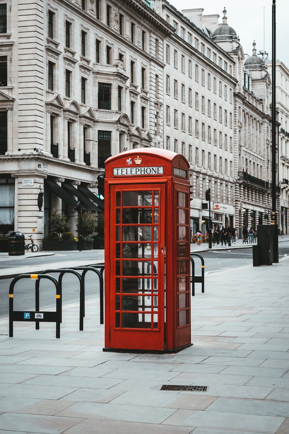 Red telephone booth near white concrete building during daytime photo