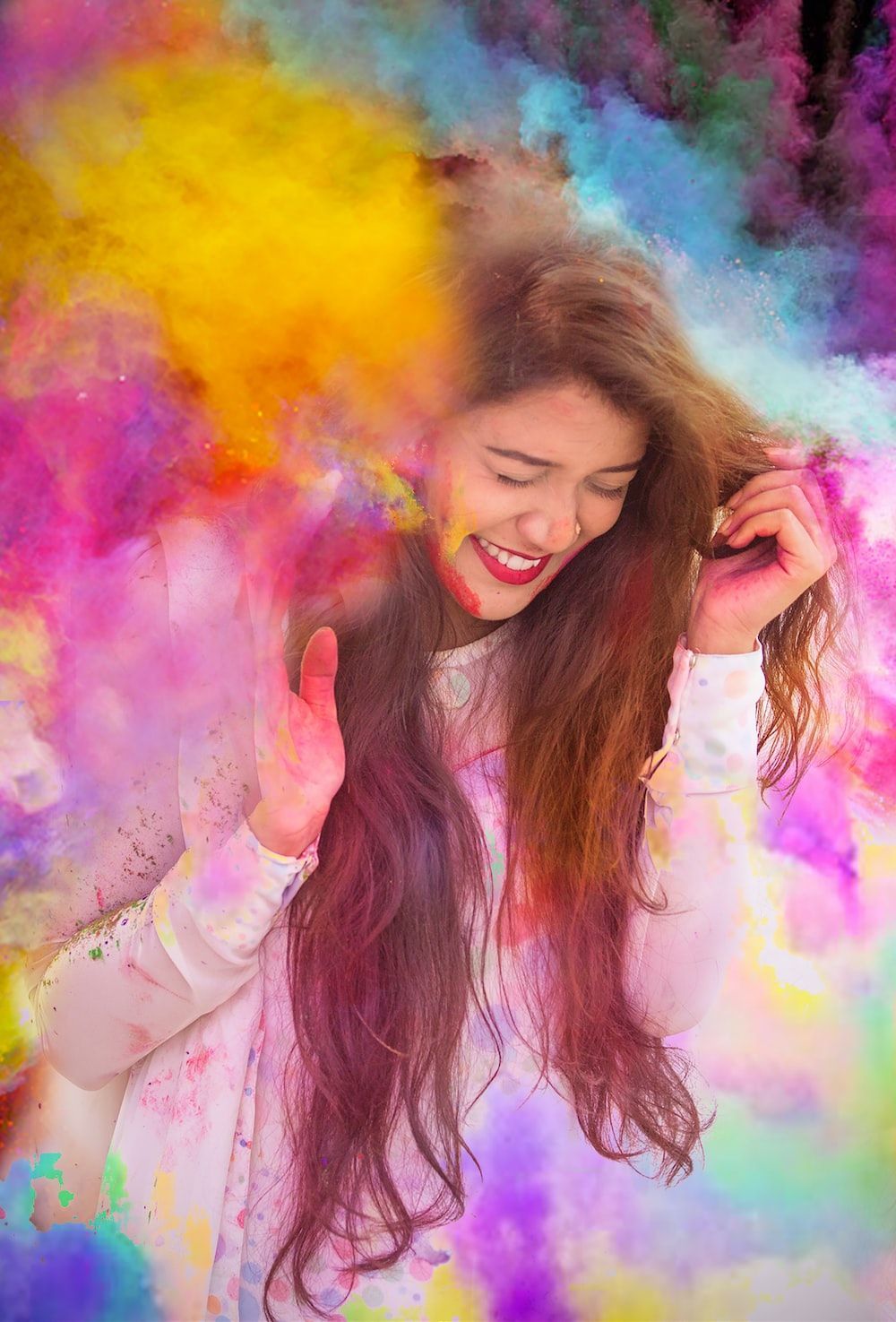 Woman in white long sleeve shirt with purple yellow and blue powder on her face photo